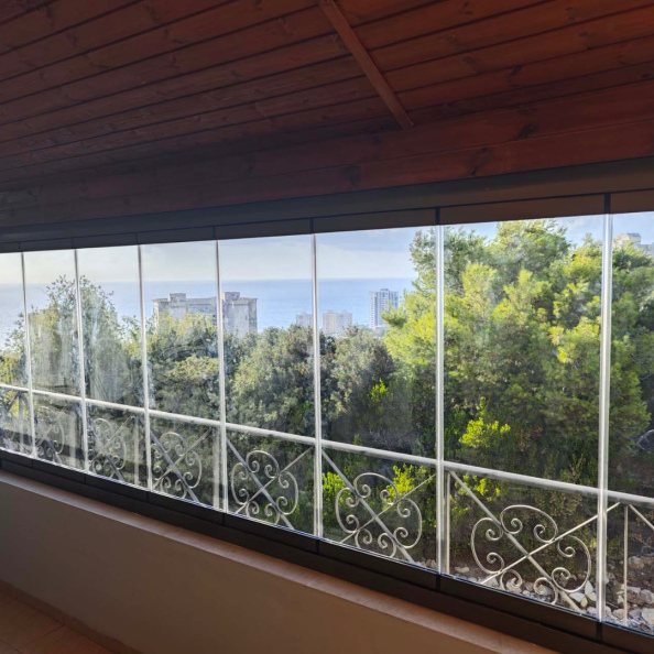 זיגוג מרפסת עם פרגולת עץ בחיפה באמצעות מערכת ללא מסגרות